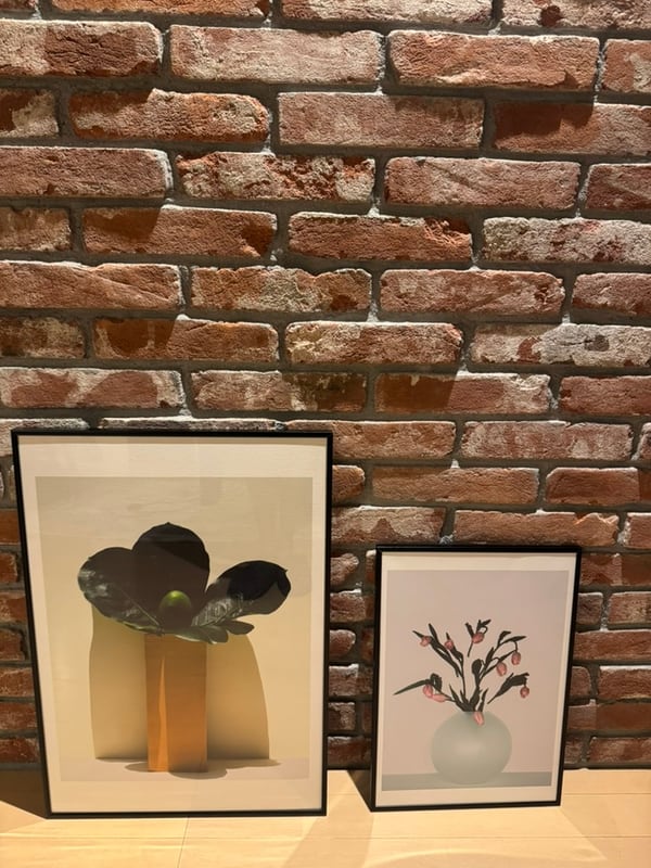Framed prints leaning against a brick wall